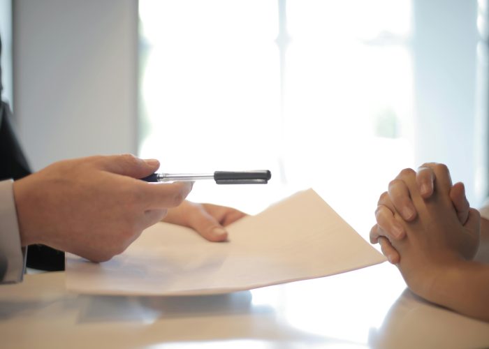 Close-up of a contract signing with hands over documents. Professional business interaction.